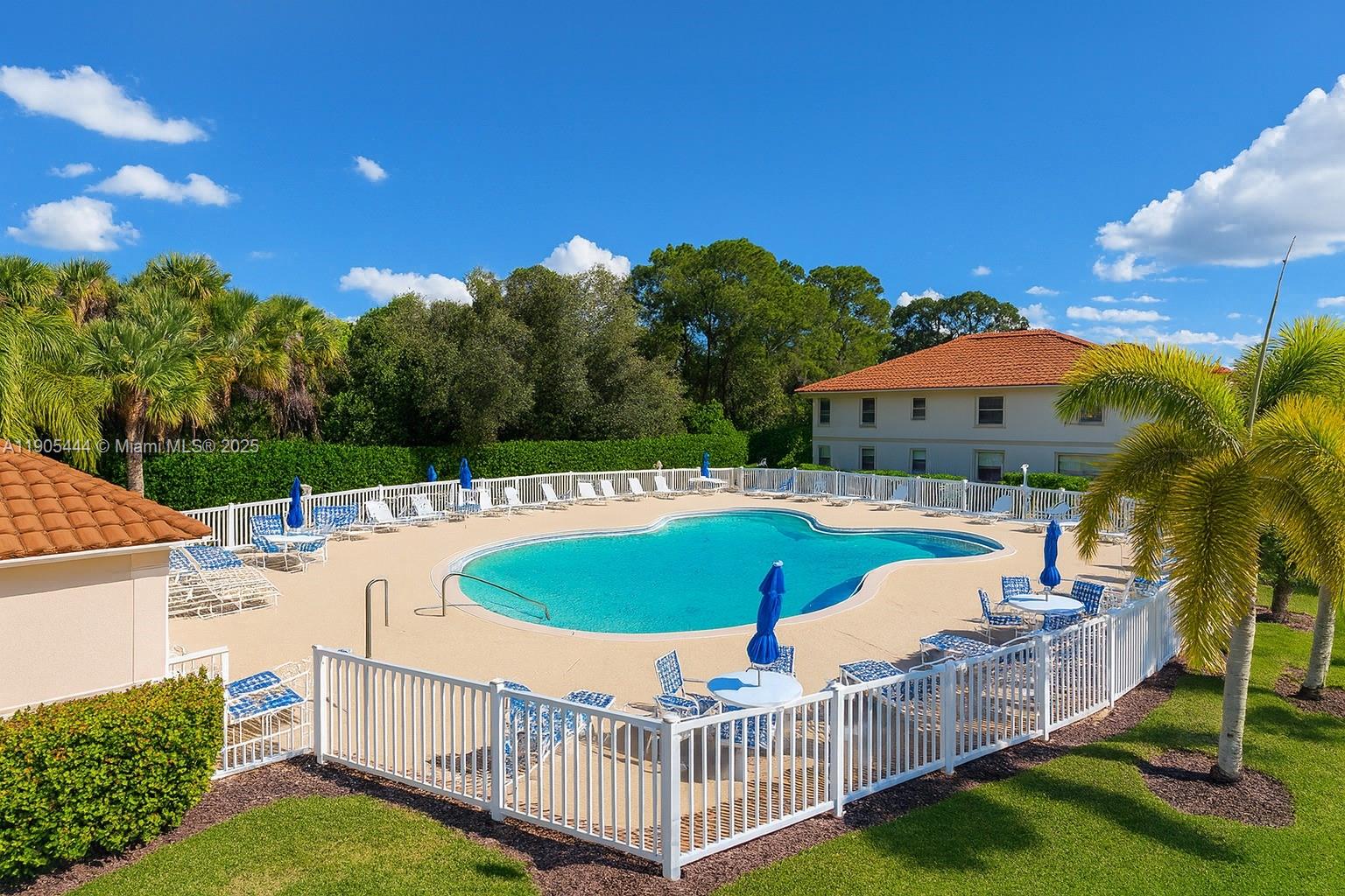 An outdoor swimming pool surrounded by a white fence, lounge chairs, and umbrellas — OTHER CITY - IN THE STATE OF FLORIDA, FL