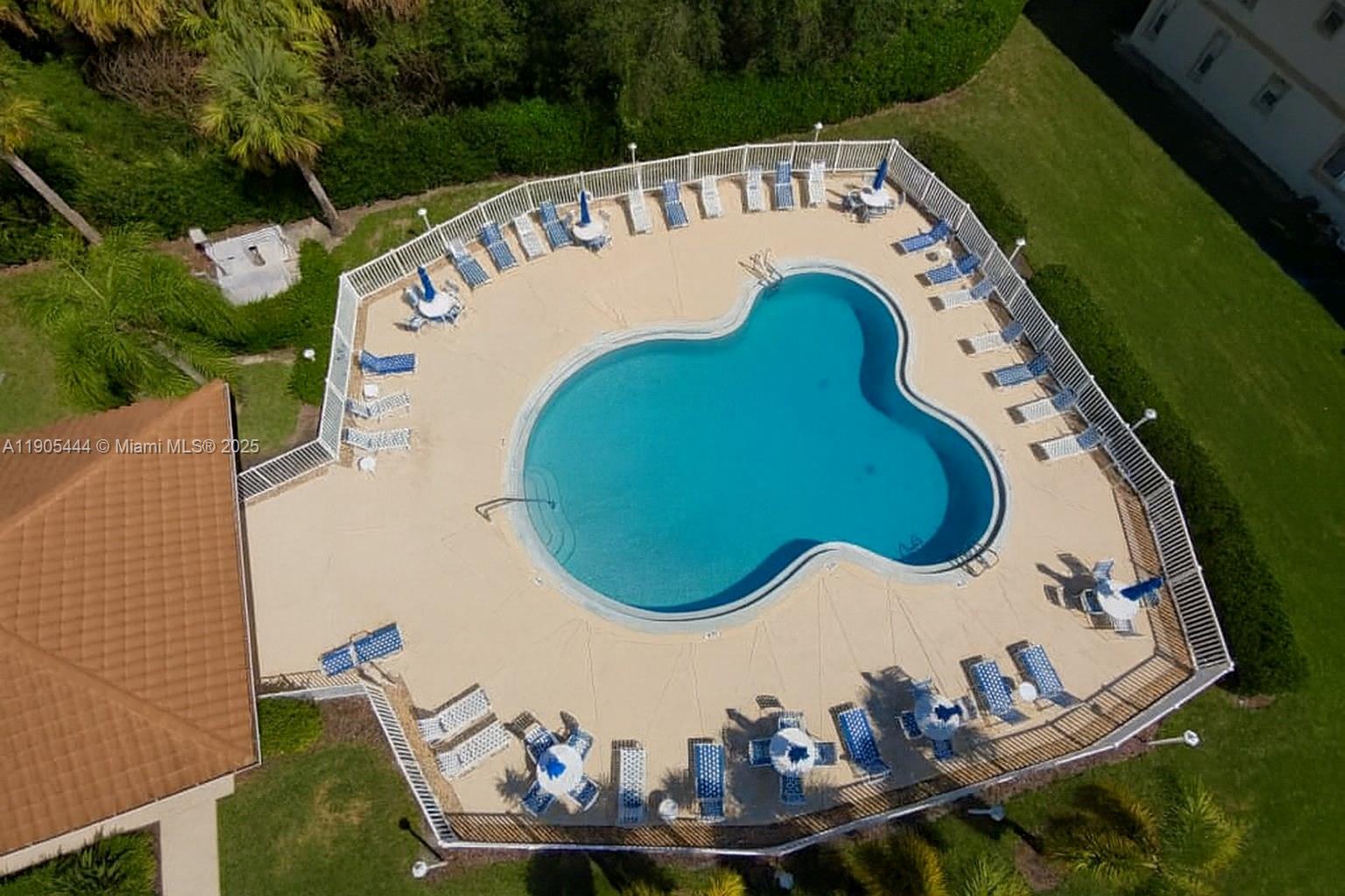 An aerial view shows a clover-shaped swimming pool surrounded by lounge chairs and a fence — OTHER CITY - IN THE STATE OF FLORIDA, FL