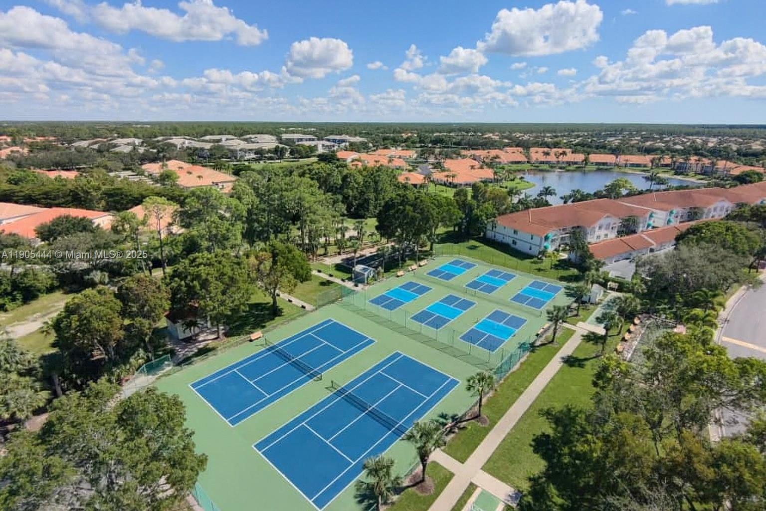 An aerial view shows multiple blue tennis courts surrounded by trees and residential buildings — OTHER CITY - IN THE STATE OF FLORIDA, FL