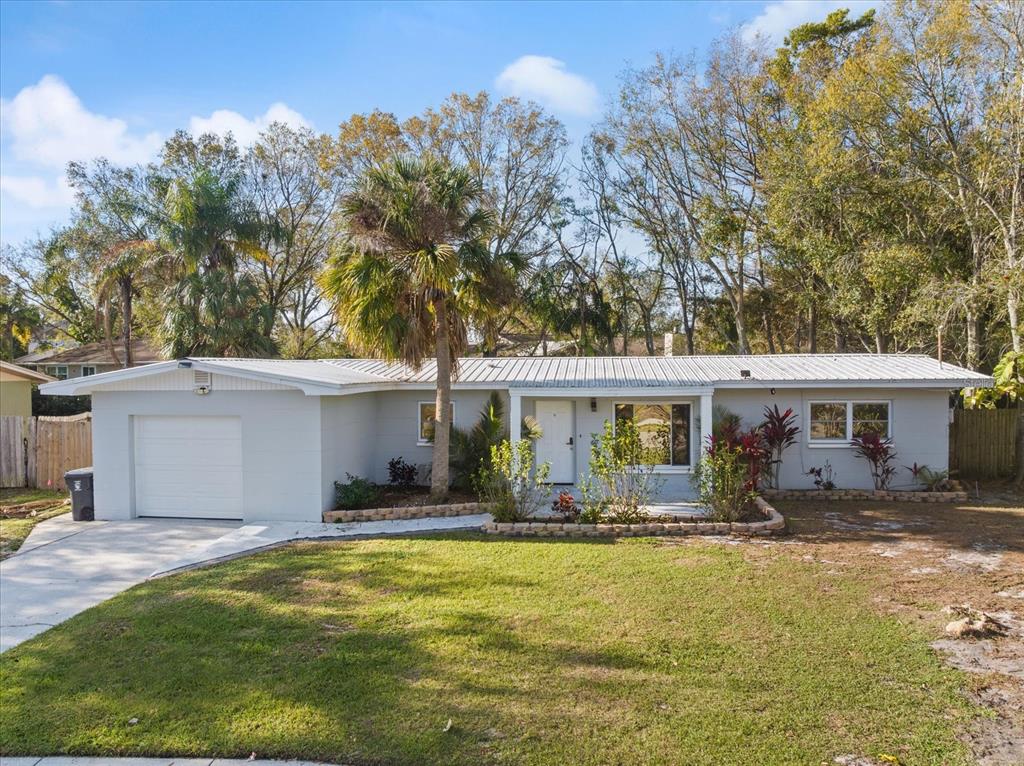 A single-story house with a white exterior, metal roof, and an attached garage — 432 COUNTRY CLUB DRIVE, OLDSMAR, FL