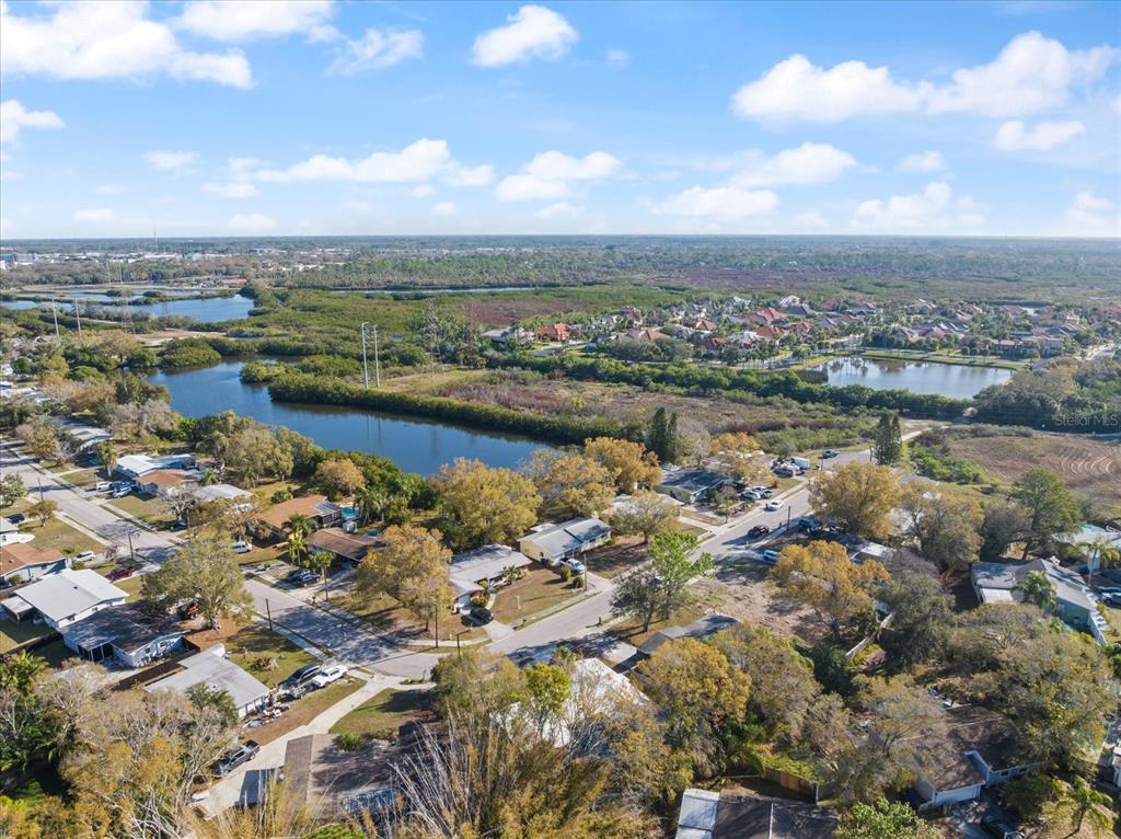 An aerial view shows a residential neighborhood bordering a large pond and marshy green space — 432 COUNTRY CLUB DRIVE, OLDSMAR, FL