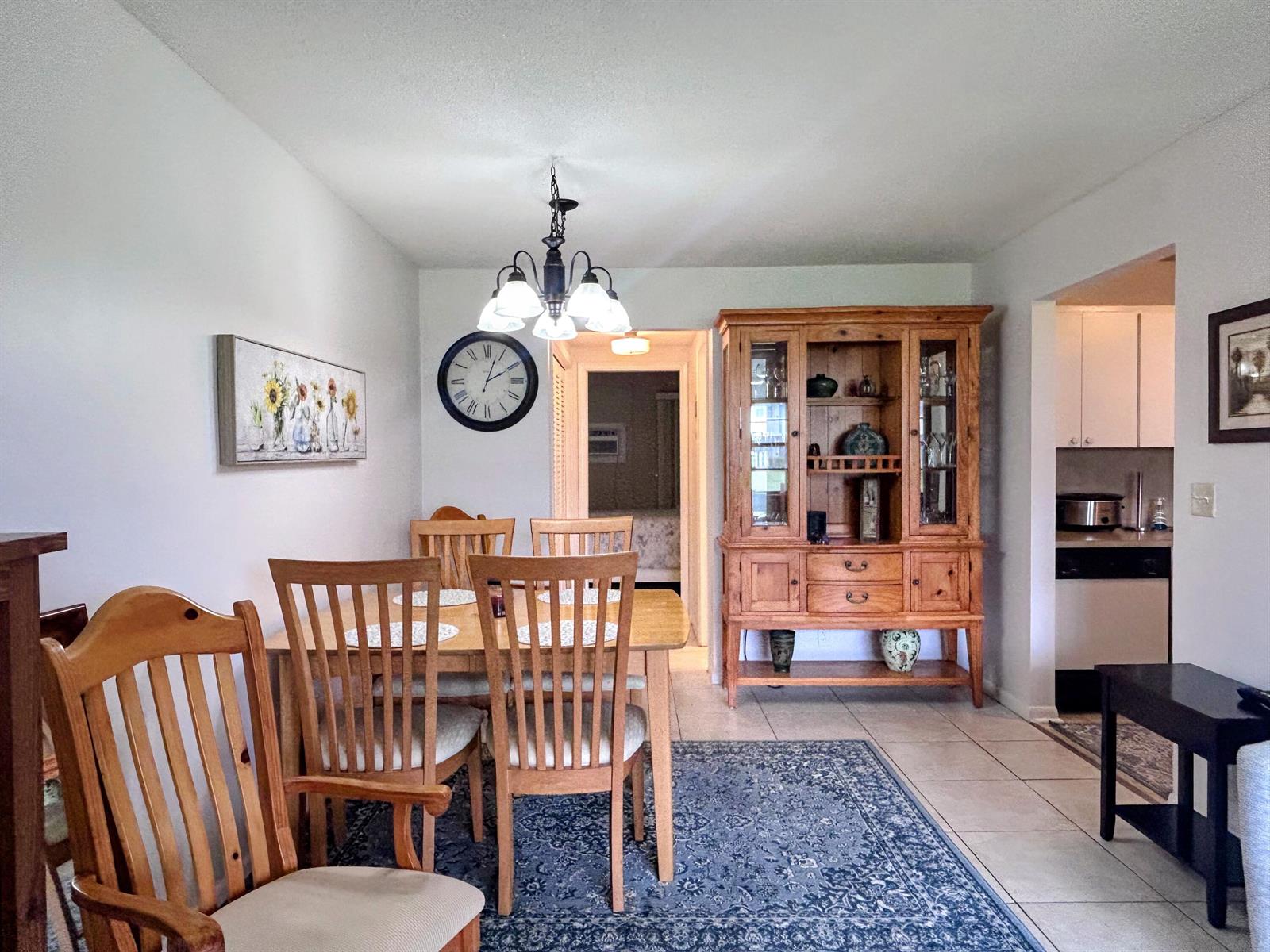 A dining room features a wooden table and chairs, a hutch, and a blue area rug — 680 W Horizons W # 103, Boynton Beach FL 33435, BOYNTON BEACH, FL