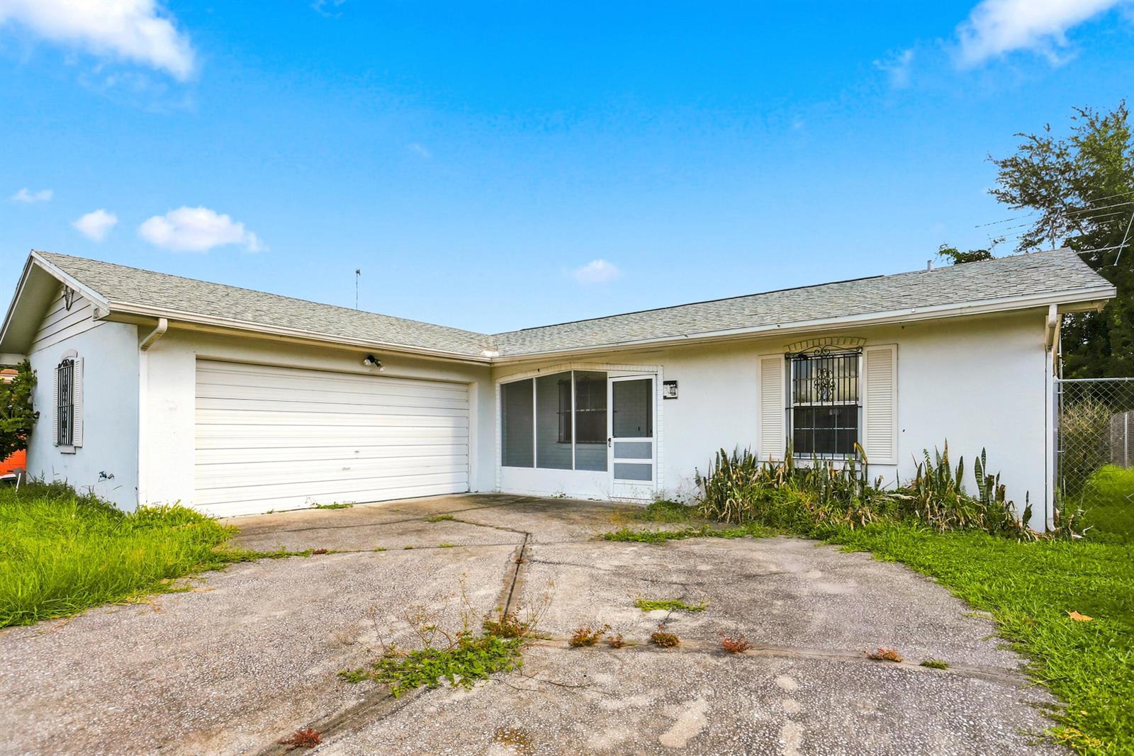 A single-story white house with a garage, screened porch, and a cracked concrete driveway — 2737 Myakka Drive, Orlando FL 32839, ORLANDO, FL