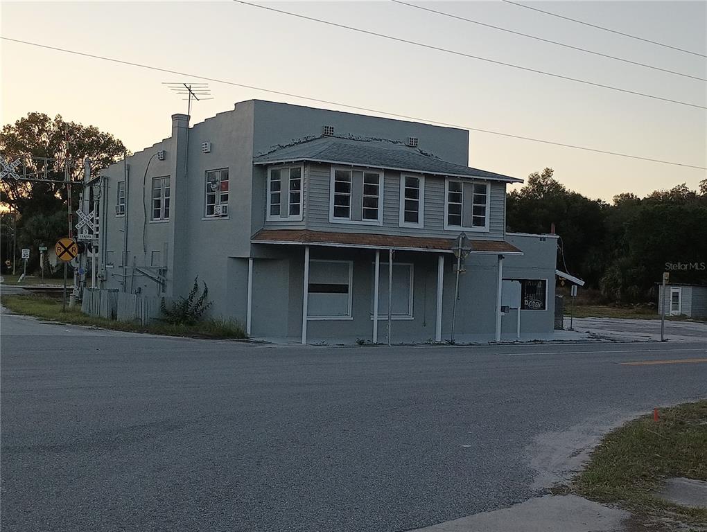 A two-story gray building stands at a street corner near a railroad crossing — 1700 US HIGHWAY 17 N, SEVILLE, FL