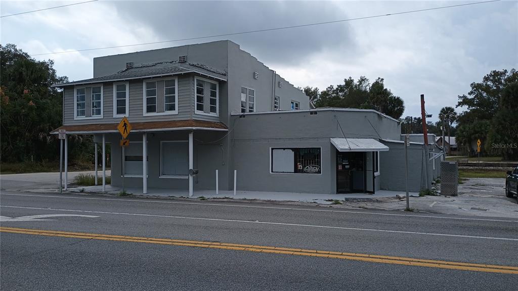 A two-story gray commercial building sits along a road with a visible open sign — 1700 US HIGHWAY 17 N, SEVILLE, FL