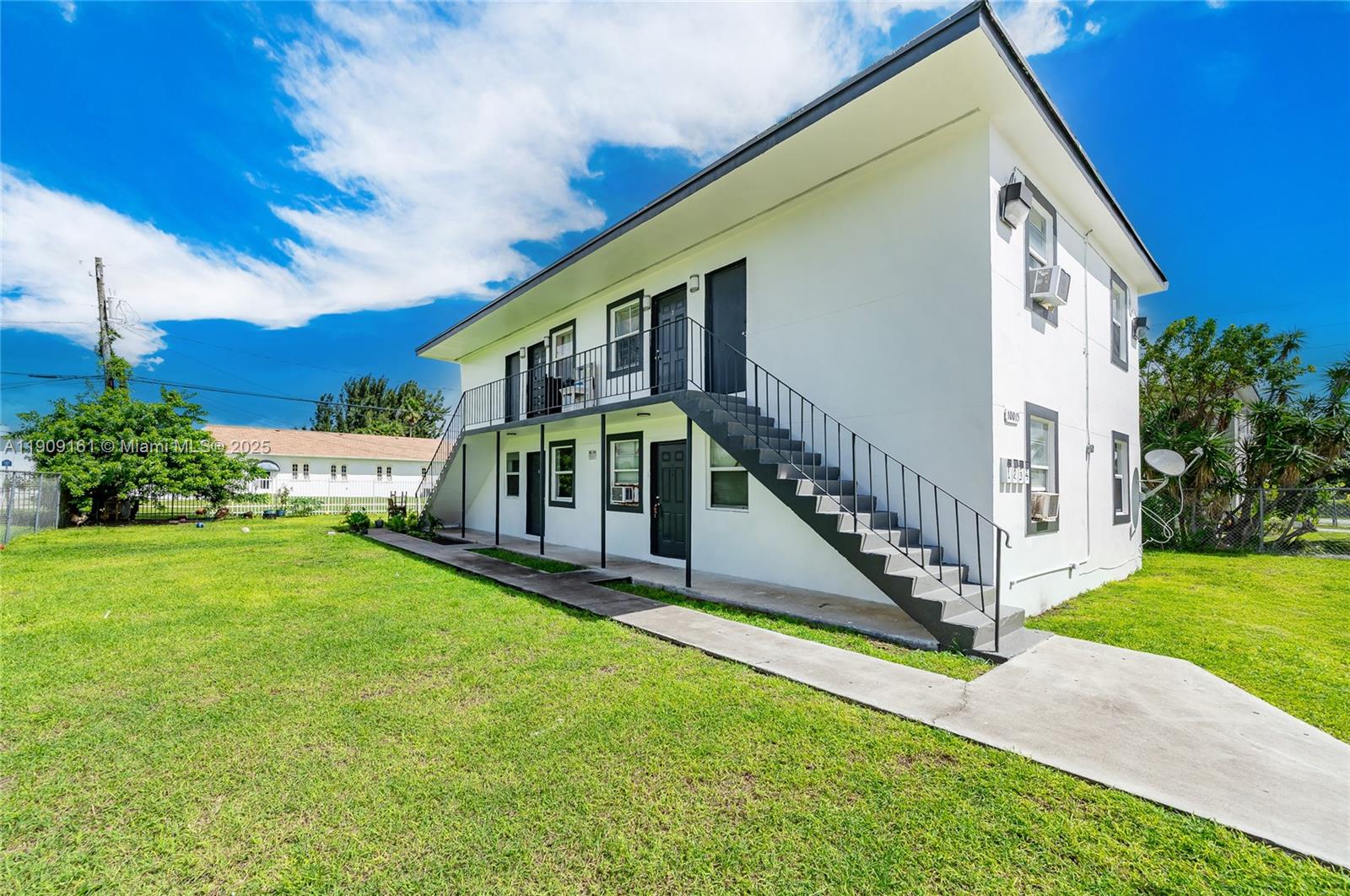 A two-story white apartment building features an exterior staircase and a surrounding grassy yard — 10015 SW 170th Ter, Miami FL 33157, MIAMI, FL