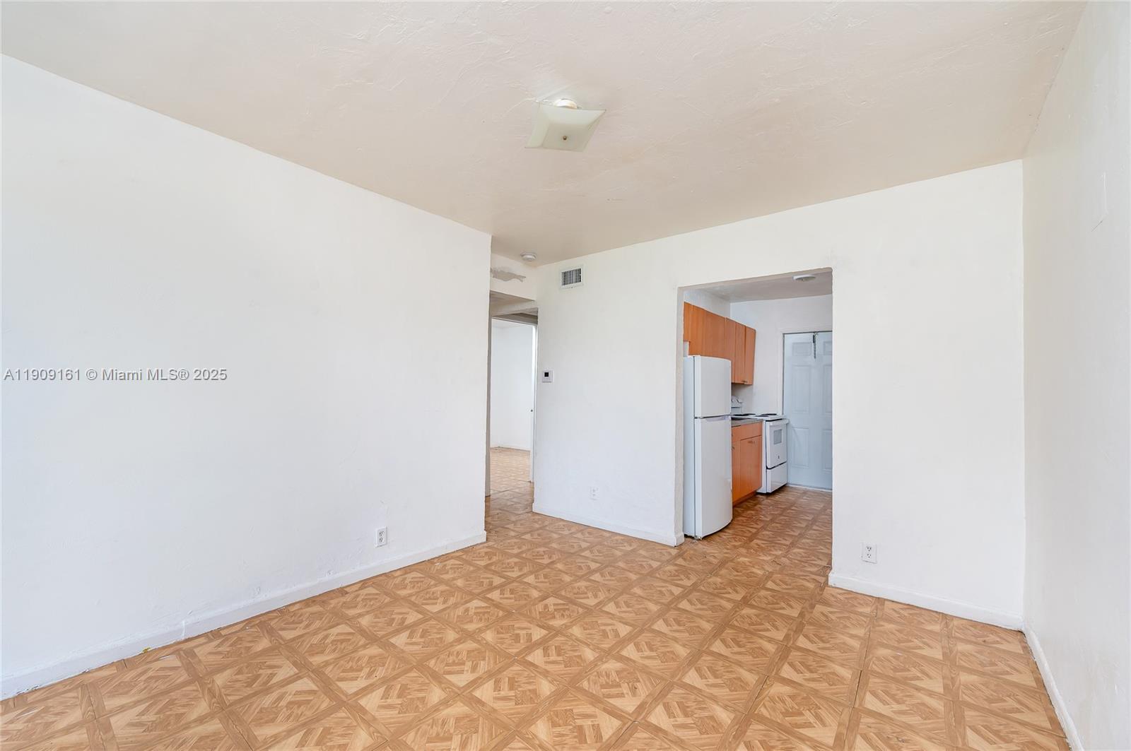 A room with light-colored walls and patterned flooring leads to a kitchen with cabinets — 10015 SW 170th Ter, Miami FL 33157, MIAMI, FL