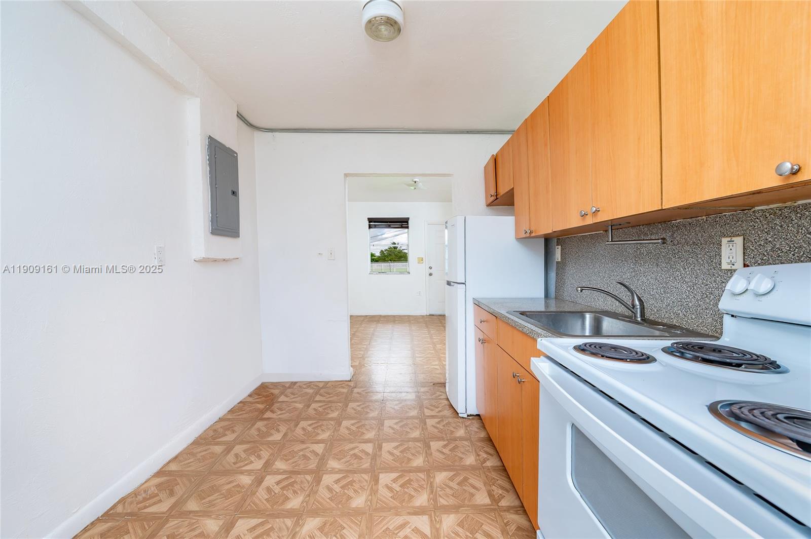 A kitchen features light wood cabinets, white appliances, and patterned tile flooring — 10015 SW 170th Ter, Miami FL 33157, MIAMI, FL