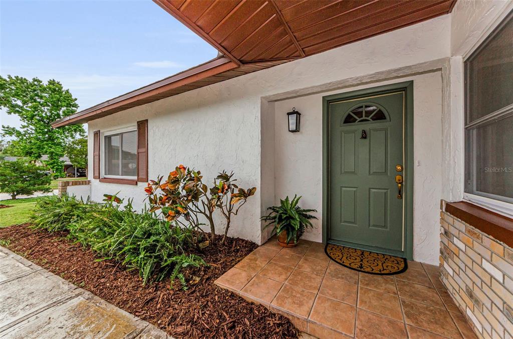 An exterior view of a home entrance with a green door and tiled porch — 1558 COTTONWOOD TERRACE, DUNEDIN, FL