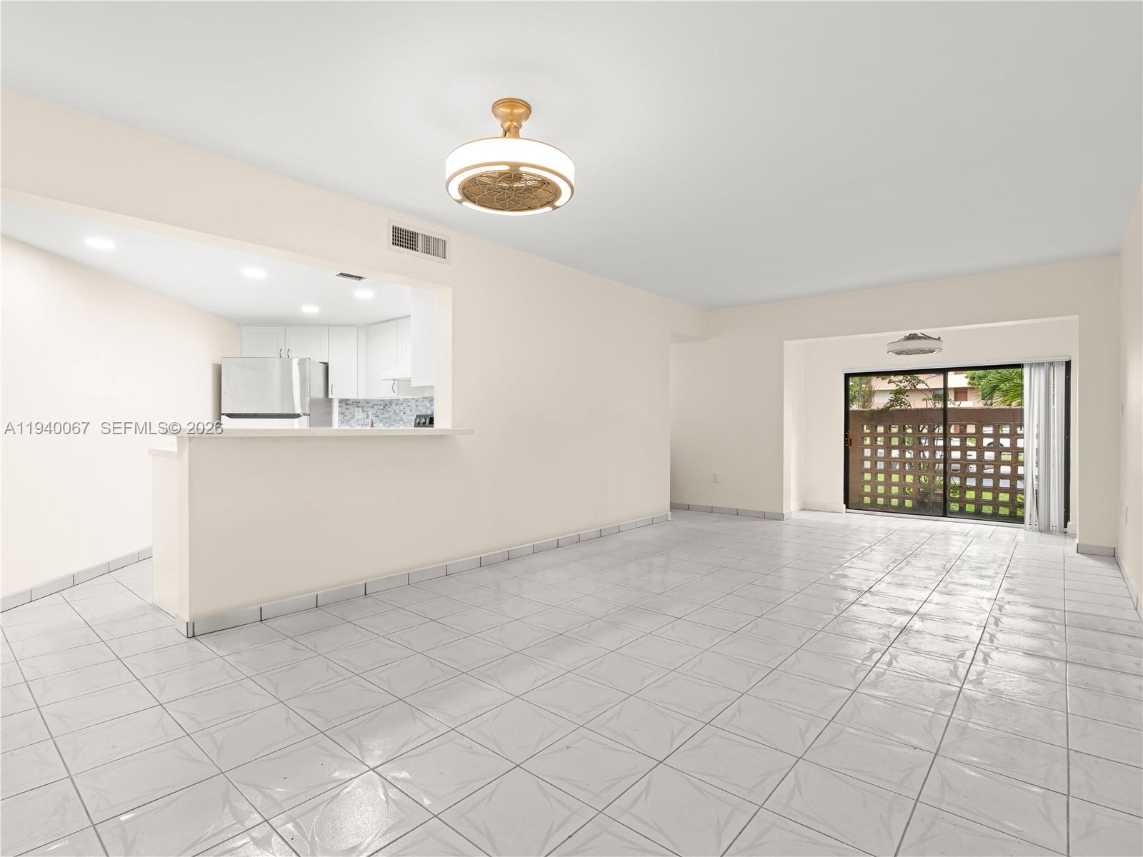 An open-concept living area features white tile floors, a kitchen pass-through, and sliding glass doors — 10249 NW 9th St Cir # 8, Miami FL 33172, MIAMI, FL