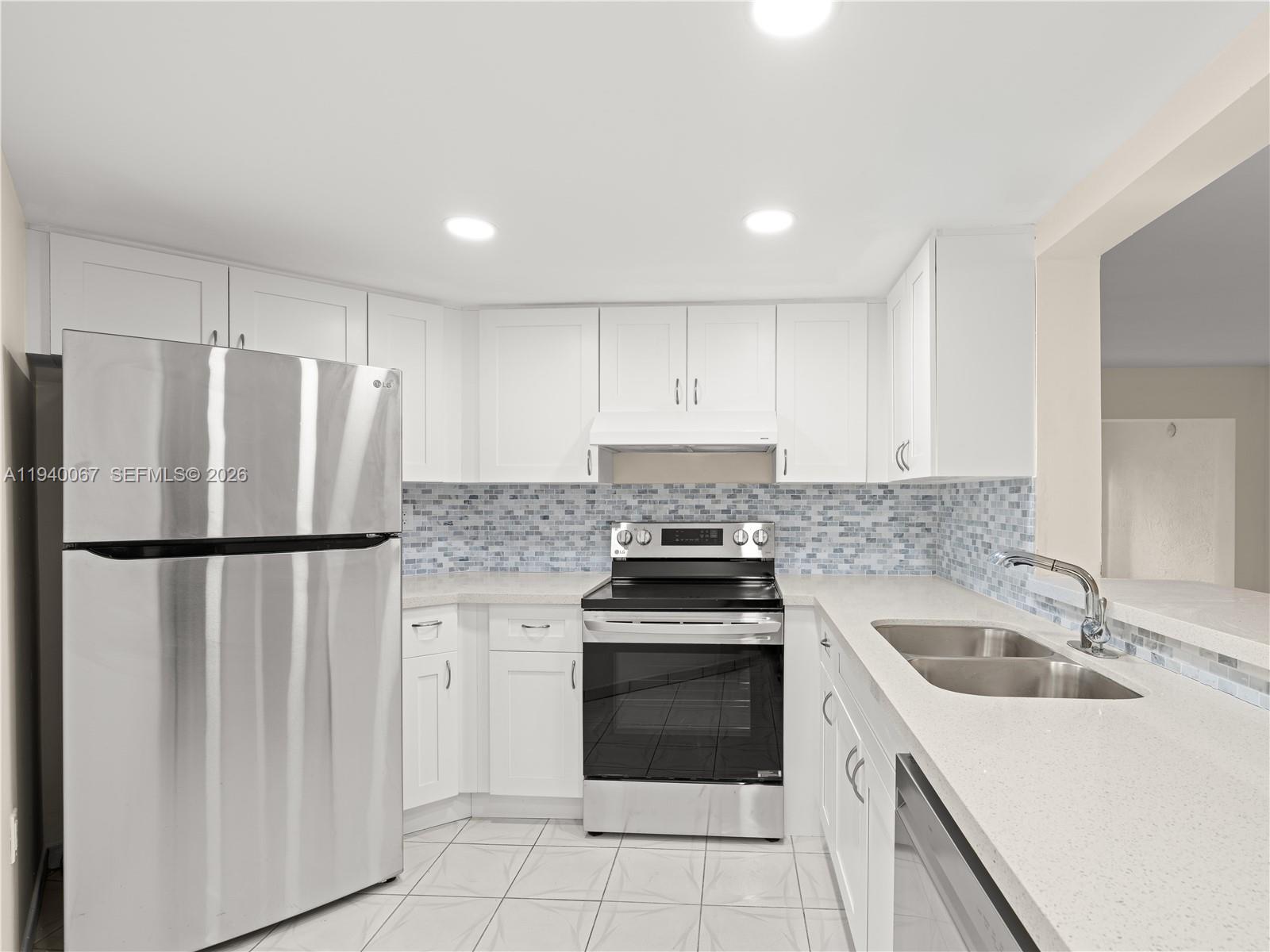 A kitchen features white cabinets, stainless steel appliances, a tiled backsplash, and light countertops — 10249 NW 9th St Cir # 8, Miami FL 33172, MIAMI, FL