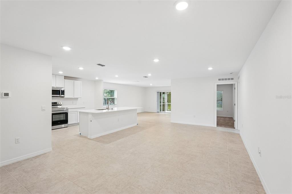 A bright, open-concept kitchen and living area with white cabinetry, tile flooring, and recessed lighting — 20247 ANDOVER AVENUE, PORT CHARLOTTE, FL