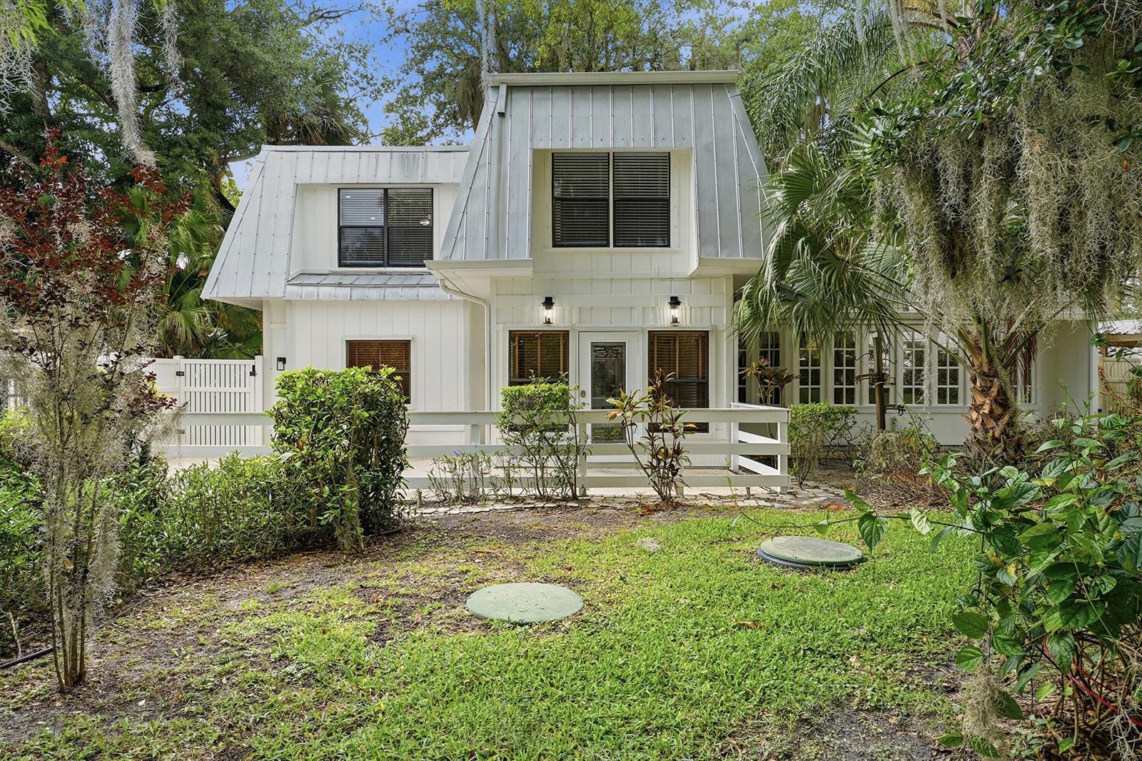 A white two-story house with a metal mansard roof and a front deck — 576 SW Rustic Circle, Stuart FL 34997, STUART, FL