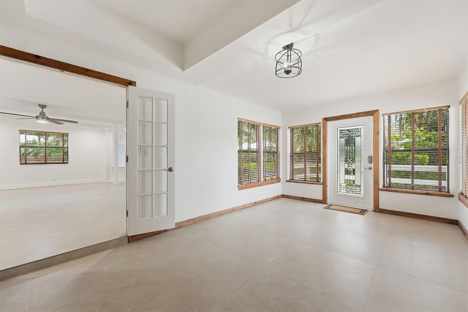 A bright entryway with white walls, tile flooring, wood trim, and a glass-paneled front door — 576 SW Rustic Circle, Stuart FL 34997, STUART, FL