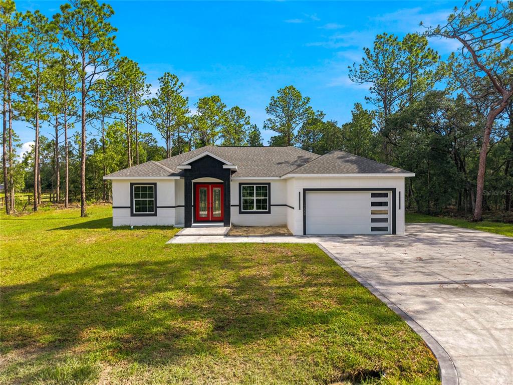 A single-story house with a white exterior, black trim, and a bright red front door — 12669 SW 81ST STREET, DUNNELLON, FL