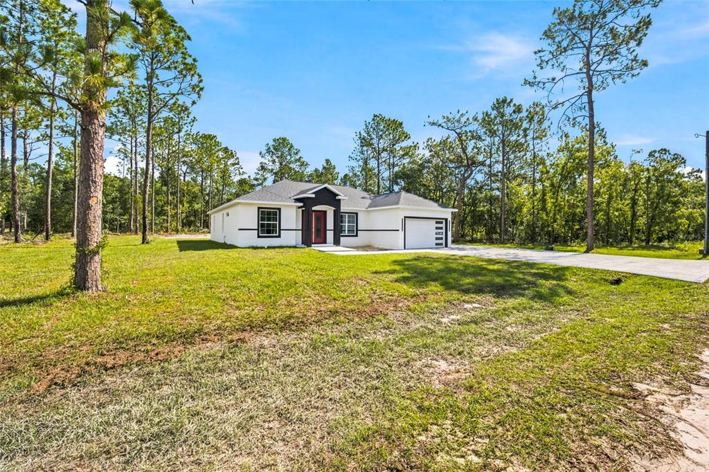 A single-story white house with a red front door sits on a grassy lot — 12669 SW 81ST STREET, DUNNELLON, FL