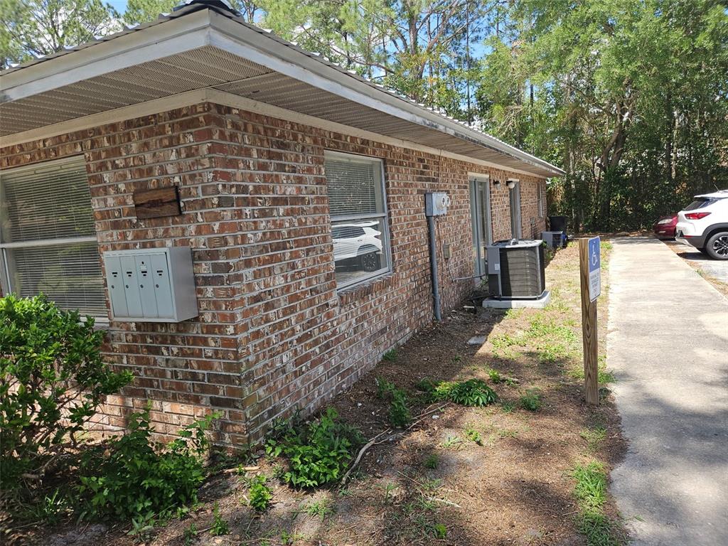 A brick exterior of a building features a metal mailbox, an air conditioning unit, and landscaping — 5813 NW 23RD TERRACE UNIT ABCD, GAINESVILLE, FL