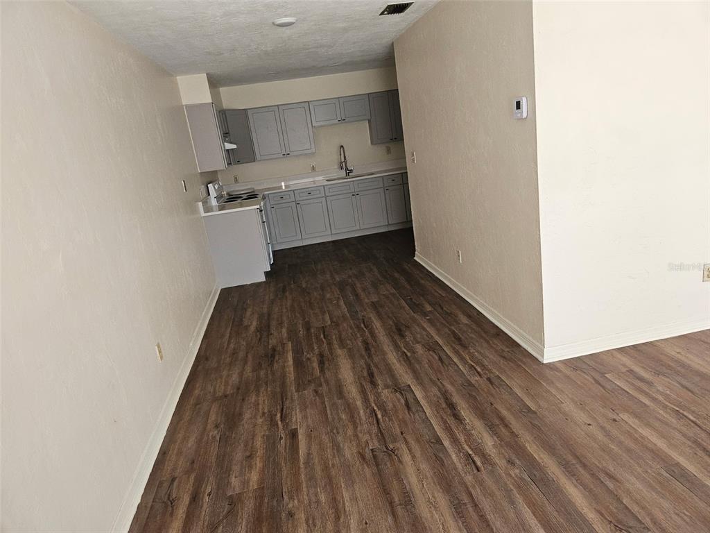 A kitchen with gray cabinets and wood-look flooring opens into a living area — 5813 NW 23RD TERRACE UNIT ABCD, GAINESVILLE, FL