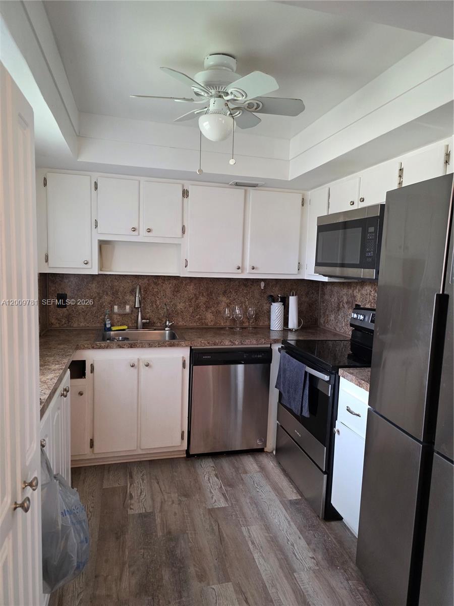A kitchen features white cabinets, stainless steel appliances, and a brown speckled countertop — 232 E Saxony E # 232, Delray Beach FL 33446, DELRAY BEACH, FL