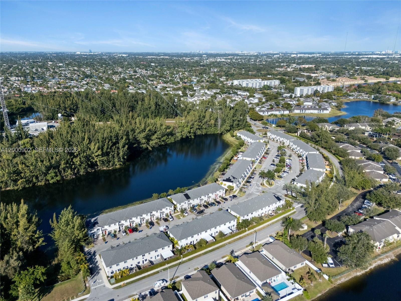 An aerial view shows a residential complex with townhouses, a lake, and surrounding greenery — 1061 NW 208th Ter, Miami Gardens FL 33169, MIAMI GARDENS, FL