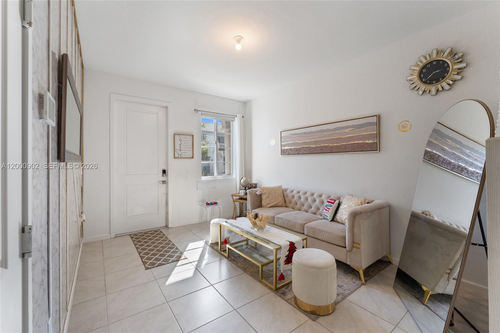A living room features a tufted beige sofa, a glass coffee table, and a floor mirror — 1061 NW 208th Ter, Miami Gardens FL 33169, MIAMI GARDENS, FL