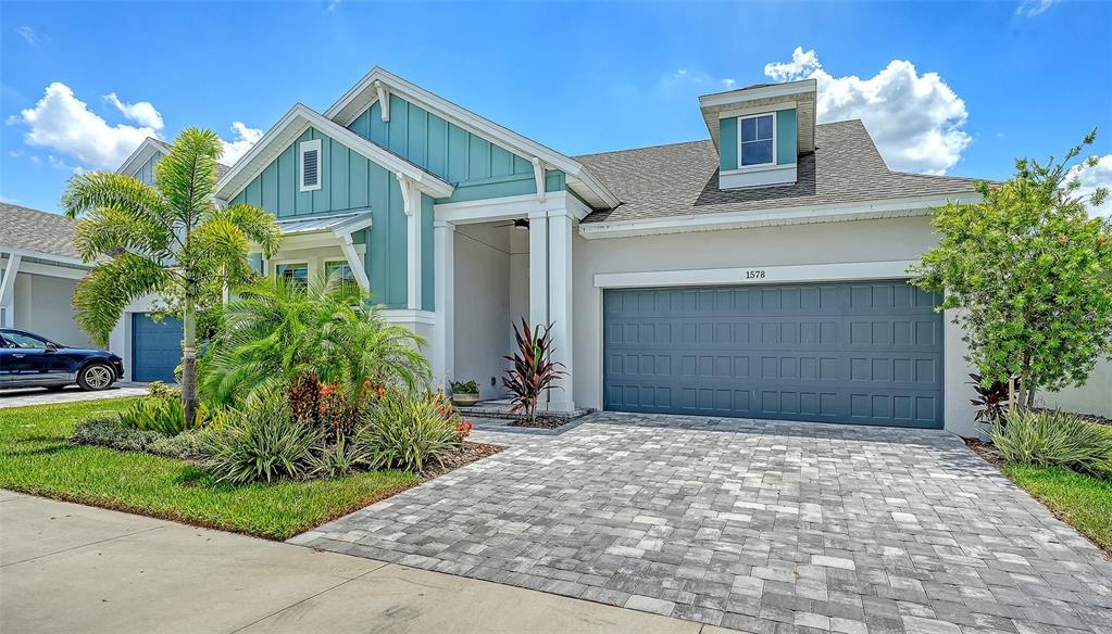 A teal and white single-story house features a palm tree and a paved driveway — 1578 RUNNING TIDE PLACE, SARASOTA, FL