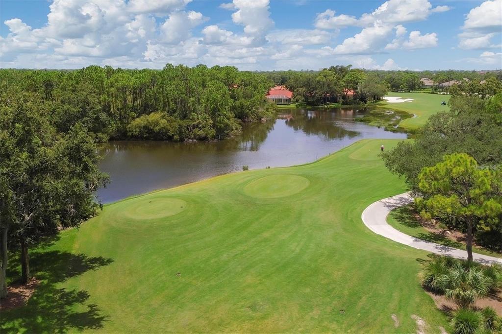 An aerial view of a golf course hole featuring a green, pond, and surrounding trees — 8750 OLDE HICKORY AVENUE UNIT 9308, SARASOTA, FL