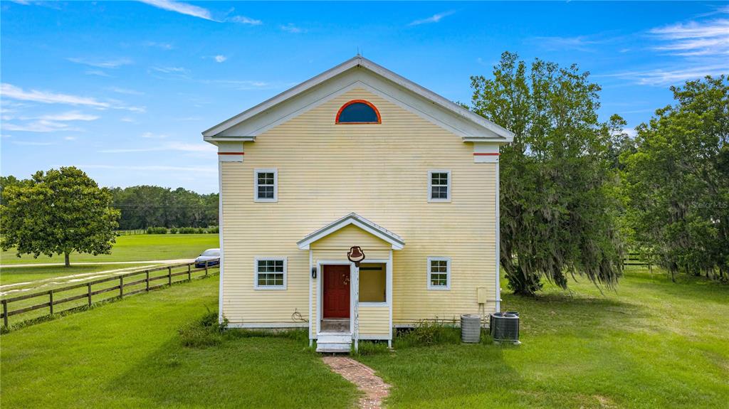 A yellow two-story house with a red front door sits on a grassy lot — 13939 N US HIGHWAY 441, CITRA, FL