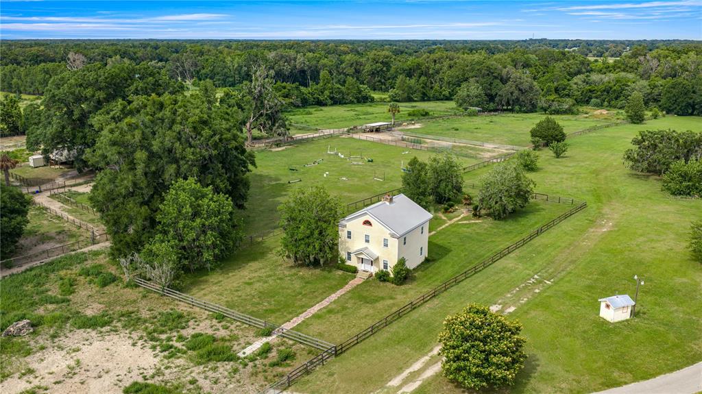 An aerial view shows a two-story house situated on a large, fenced rural property — 13939 N US HIGHWAY 441, CITRA, FL