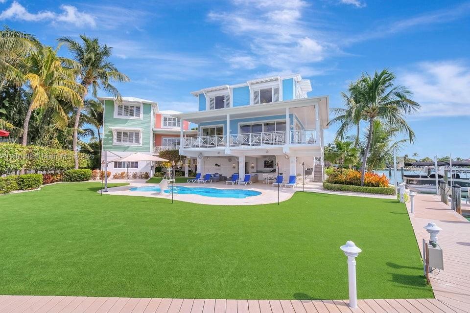 A multi-story blue and green waterfront house features a pool, lawn, and private boat dock — 162 Bayview Dr, Islamorada FL 33036, ISLAMORADA, FL