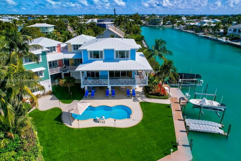 An aerial view shows a blue waterfront house with a pool, lawn, and boat dock — 162 Bayview Dr, Islamorada FL 33036, ISLAMORADA, FL
