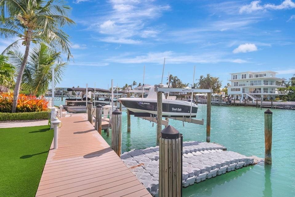 A wooden dock extends into a canal with a boat lift and a parked boat — 162 Bayview Dr, Islamorada FL 33036, ISLAMORADA, FL