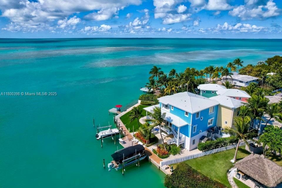 An aerial view shows a blue waterfront house with a private dock and boat lift — 162 Bayview Dr, Islamorada FL 33036, ISLAMORADA, FL