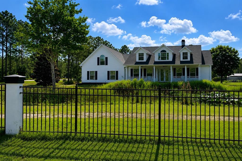 A white two-story house with a front porch sits behind a black metal fence — 3267 BANCROFT BOULEVARD UNIT 1A, ORLANDO, FL