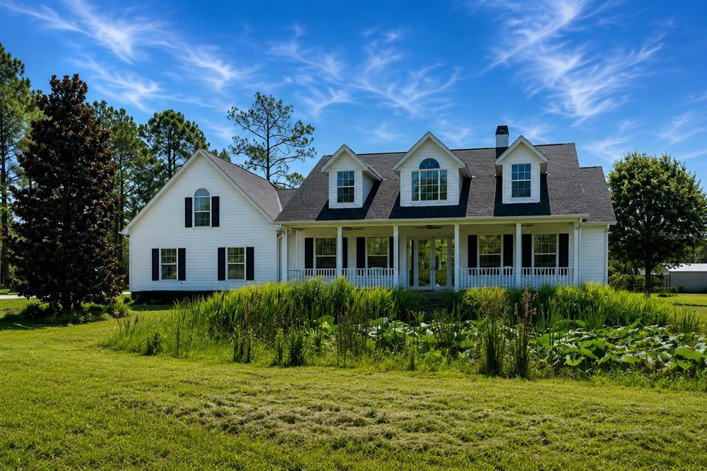 A white two-story house with a front porch sits behind a grassy pond area — 3267 BANCROFT BOULEVARD UNIT 1A, ORLANDO, FL