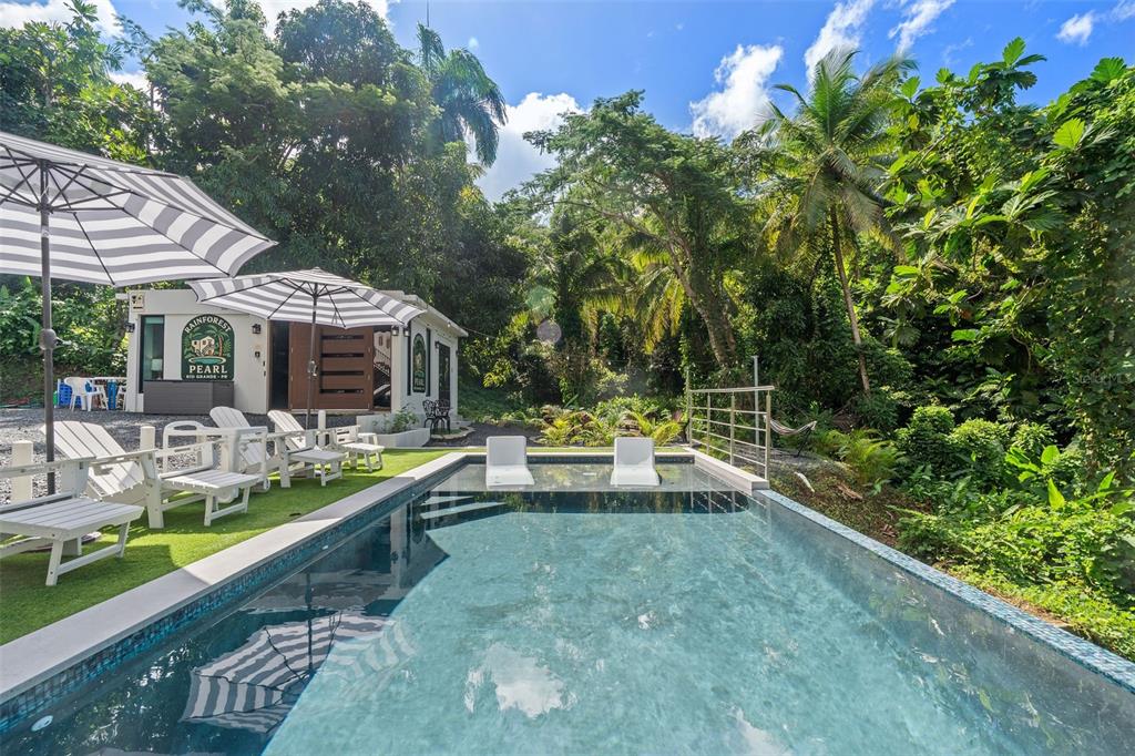 An outdoor swimming pool with lounge chairs sits in front of a small building — CARR 966 KM 2.8 BO JIMENEZ, RIO GRANDE, PR