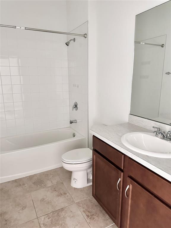 A bathroom features a white tub-shower combo, a toilet, and a vanity with a mirror — 5326 MADDIE DRIVE, HAINES CITY, FL