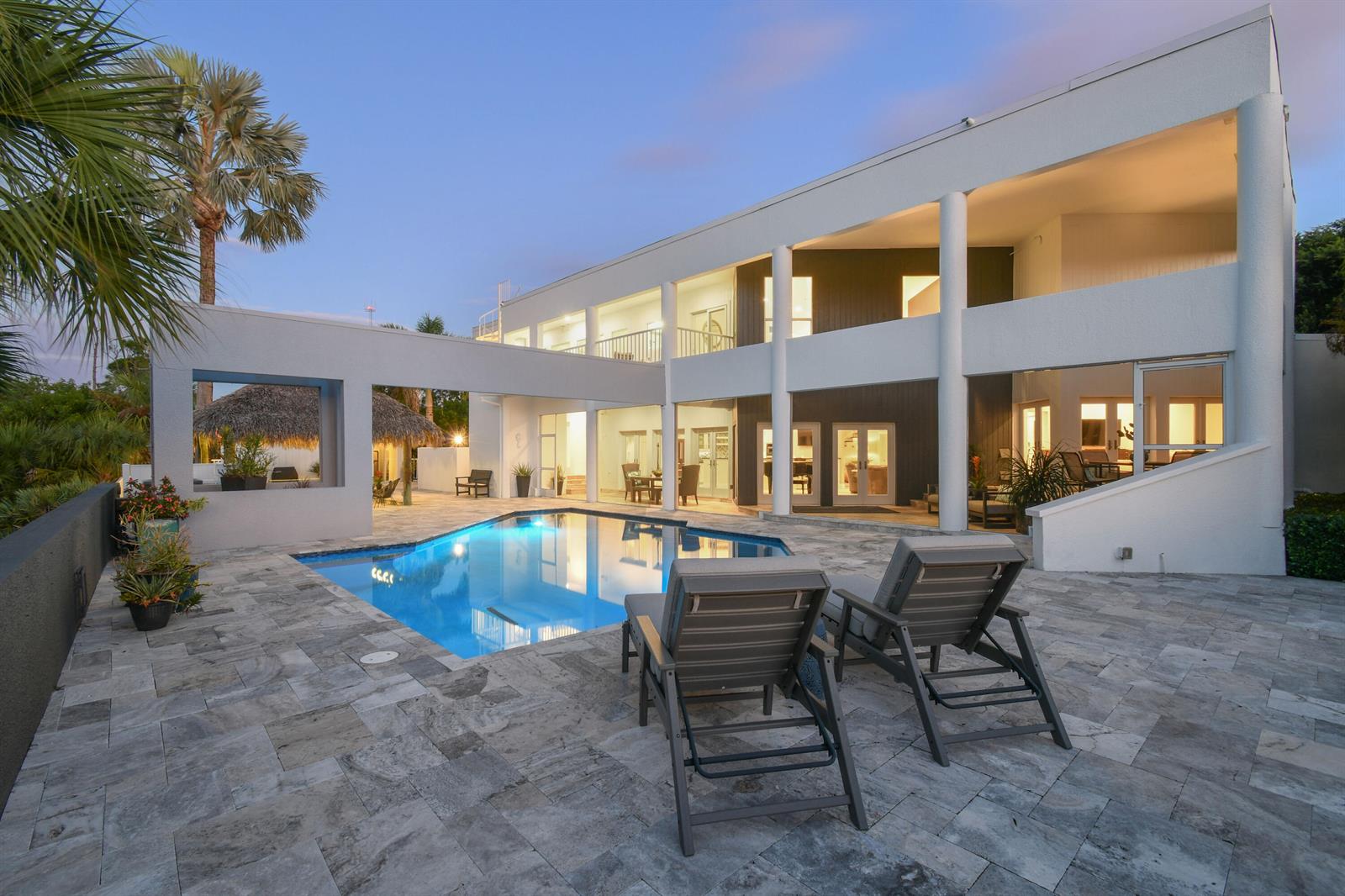 A two-story white house features a swimming pool, stone patio, and two lounge chairs — 10561 SE Le Parc, Jupiter FL 33469, JUPITER, FL