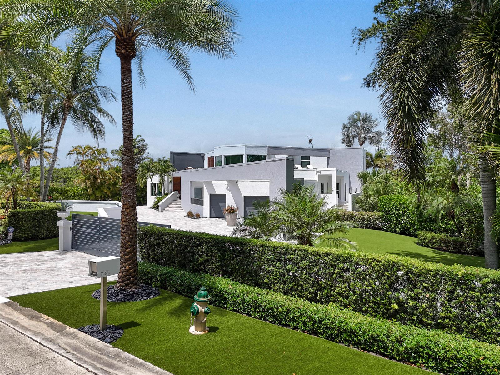 A modern white house with a paved driveway, palm trees, and a manicured hedge — 10561 SE Le Parc, Jupiter FL 33469, JUPITER, FL