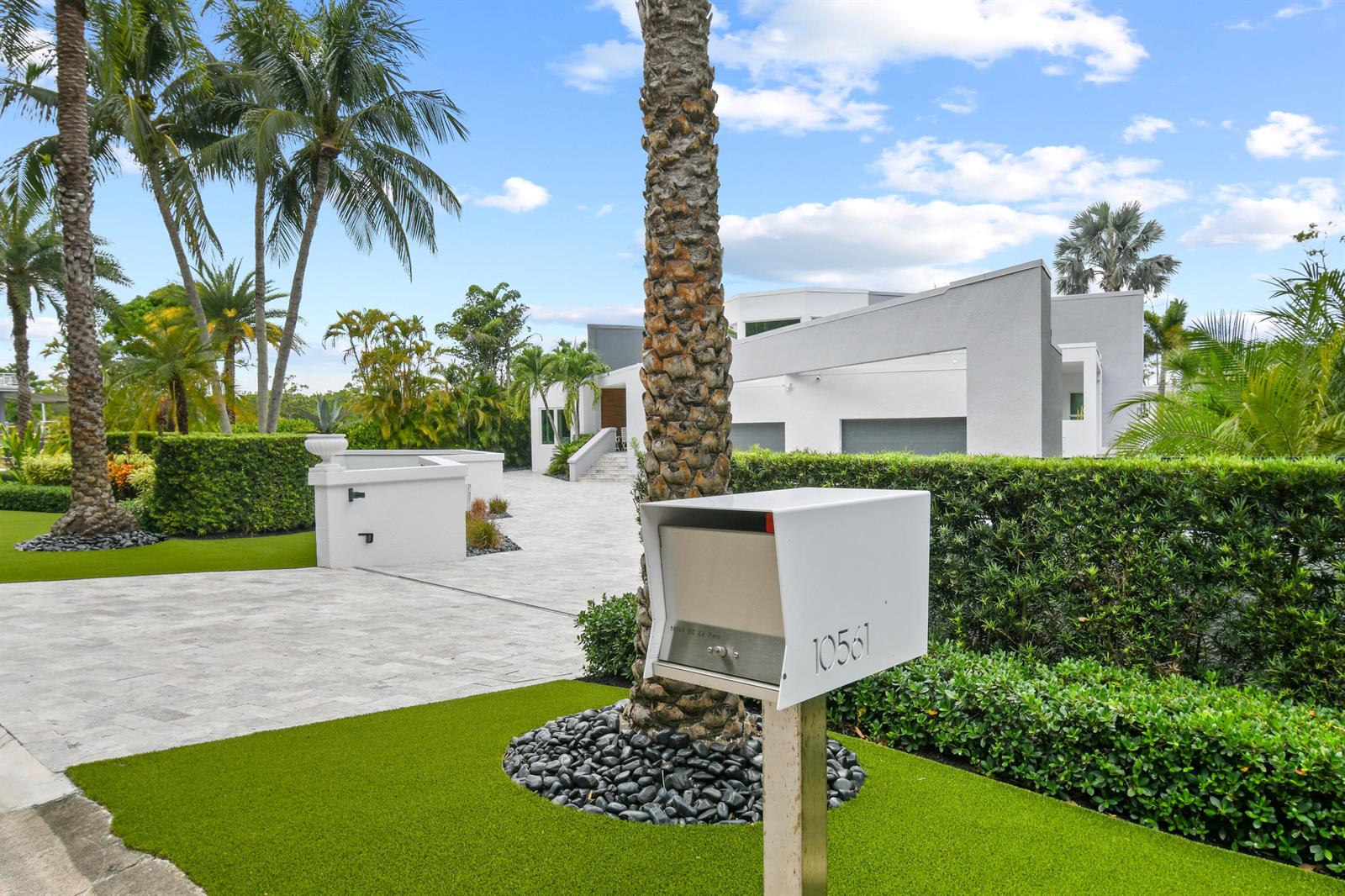 A modern white house with a paved driveway and palm trees behind a mailbox — 10561 SE Le Parc, Jupiter FL 33469, JUPITER, FL
