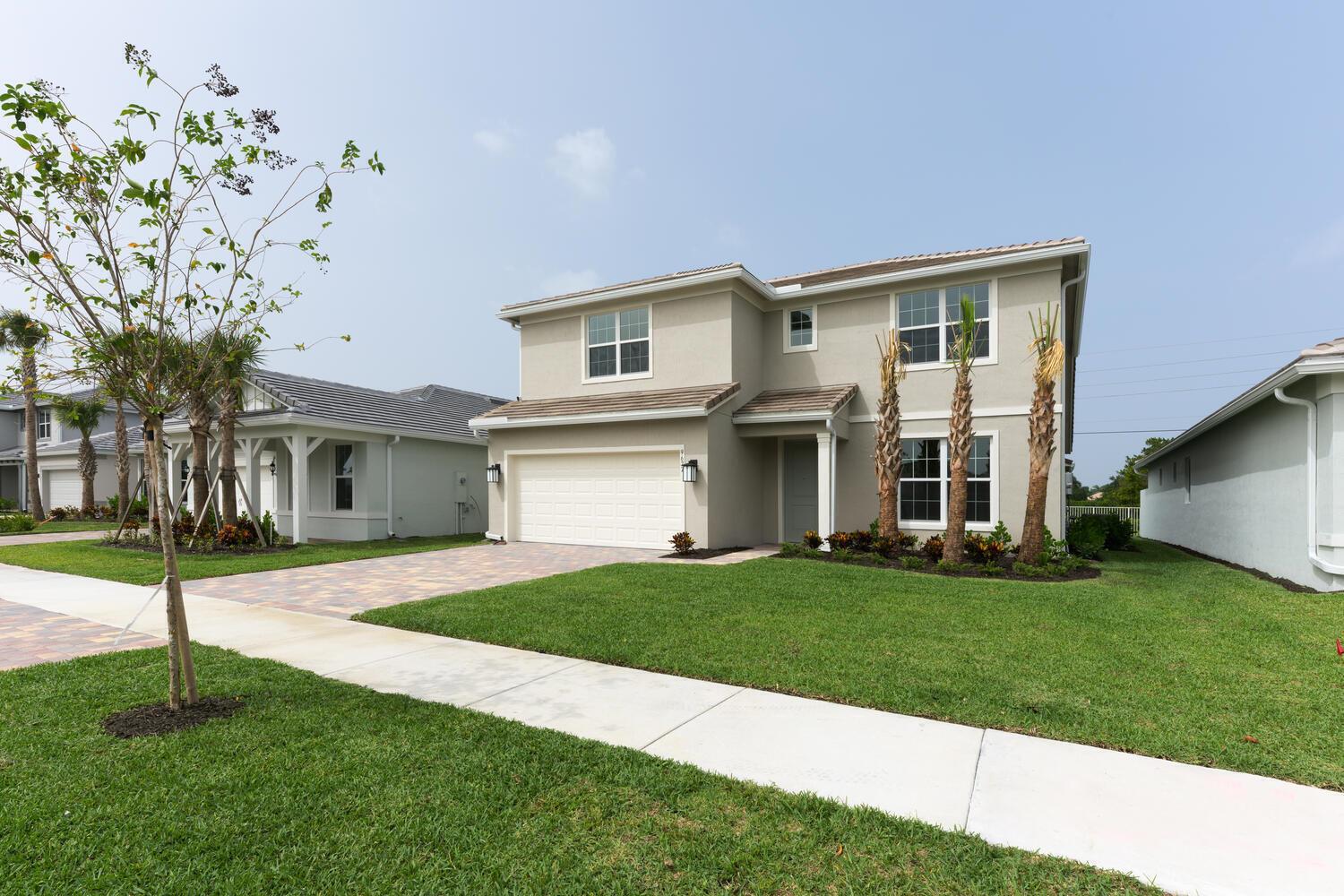 A two-story beige house with a two-car garage and palm trees in the front yard — 9677 Mosler Trail, Lake Worth FL 33467, LAKE WORTH, FL