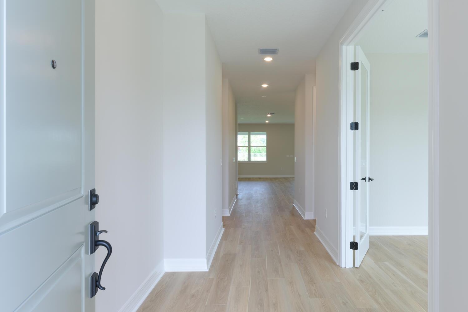 A bright entryway with light wood-look flooring leads into a hallway with recessed lighting — 9677 Mosler Trail, Lake Worth FL 33467, LAKE WORTH, FL