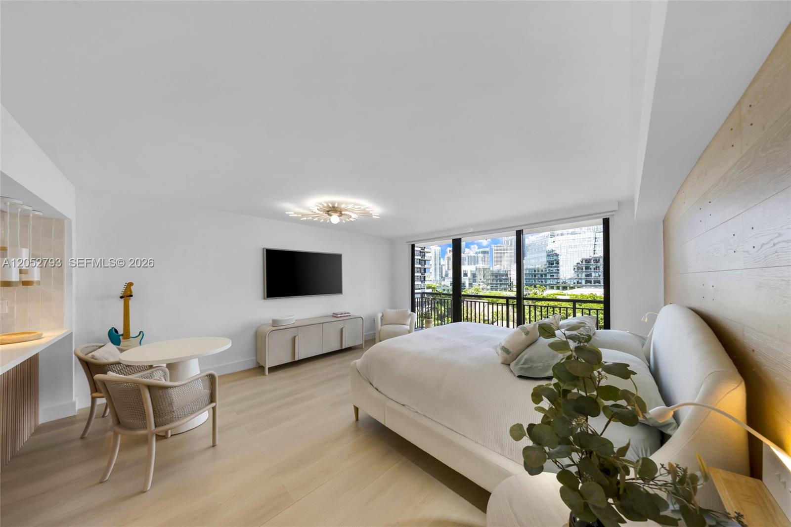 A modern bedroom features light wood flooring, a white bed, and a city view balcony — 540 Brickell Key Dr # 809, Miami FL 33131, MIAMI, FL