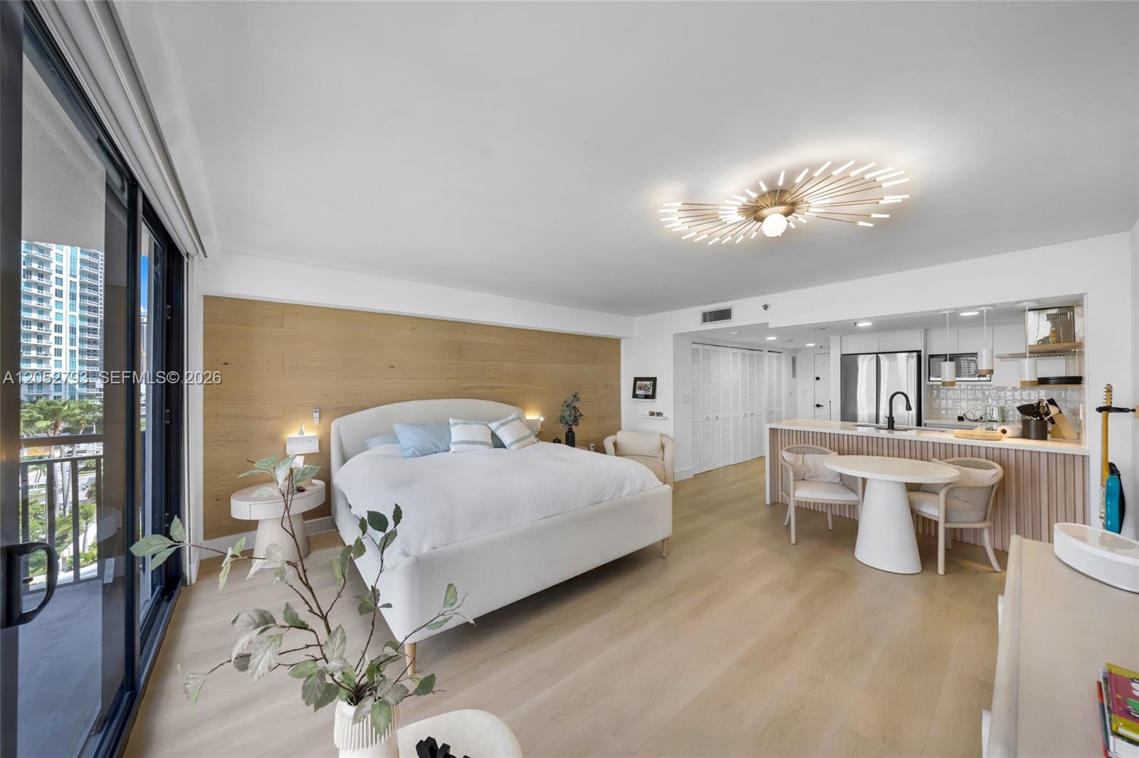 A studio apartment features a bed, a dining area, and a kitchen with light wood flooring — 540 Brickell Key Dr # 809, Miami FL 33131, MIAMI, FL