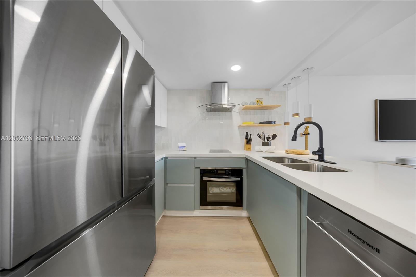 A modern kitchen features light blue cabinets, stainless steel appliances, and white countertops — 540 Brickell Key Dr # 809, Miami FL 33131, MIAMI, FL