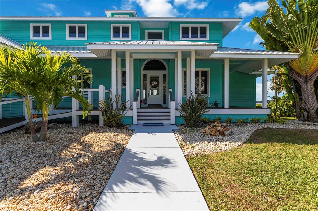 A teal two-story house with a white front porch, stairs, and a concrete walkway — 2207 5TH STREET W, PALMETTO, FL