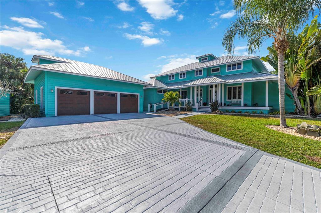 A turquoise two-story house with a metal roof and a three-car garage — 2207 5TH STREET W, PALMETTO, FL