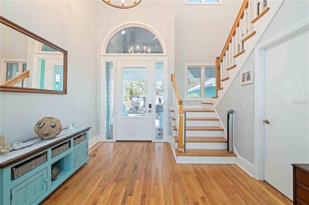An entryway features hardwood floors, a staircase with white railings, and a blue console table — 2207 5TH STREET W, PALMETTO, FL