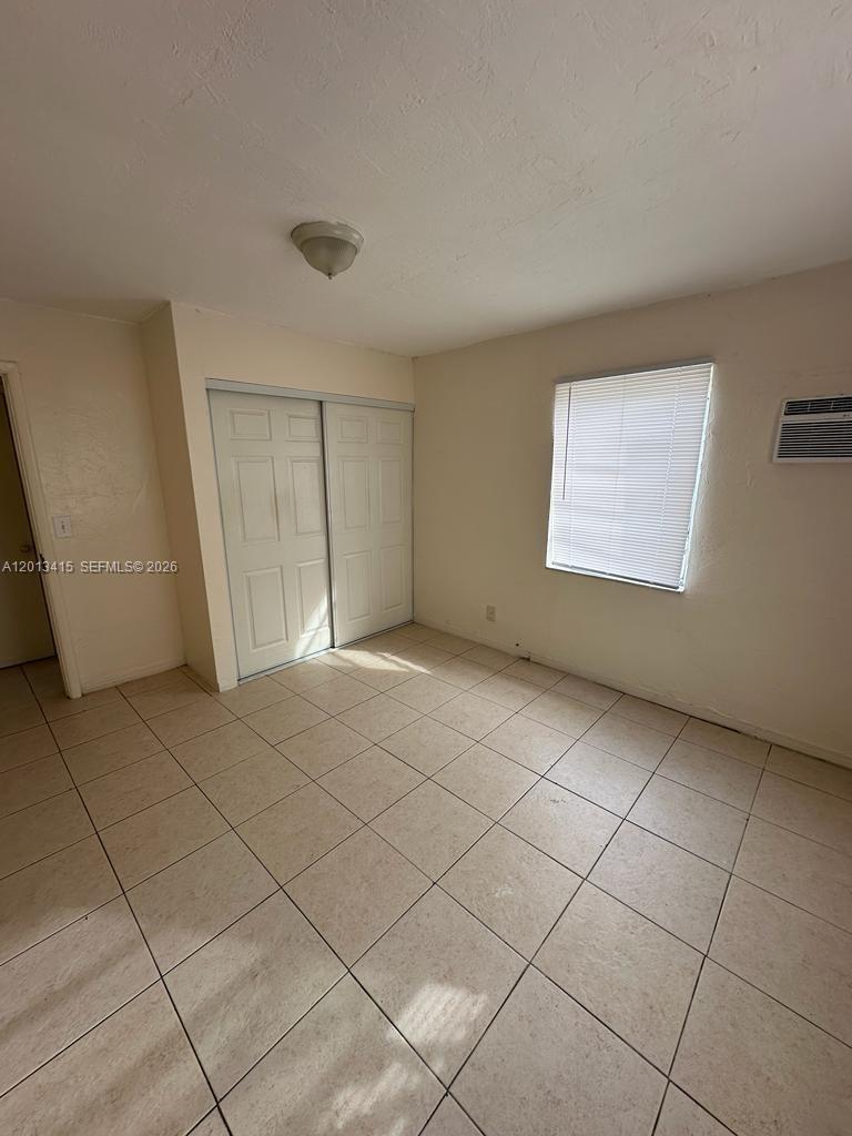 A bedroom features light-colored walls, tiled flooring, a sliding closet door, and a window — 756 NW 5th St # 1S, Hallandale Beach FL 33009, HALLANDALE BEACH, FL