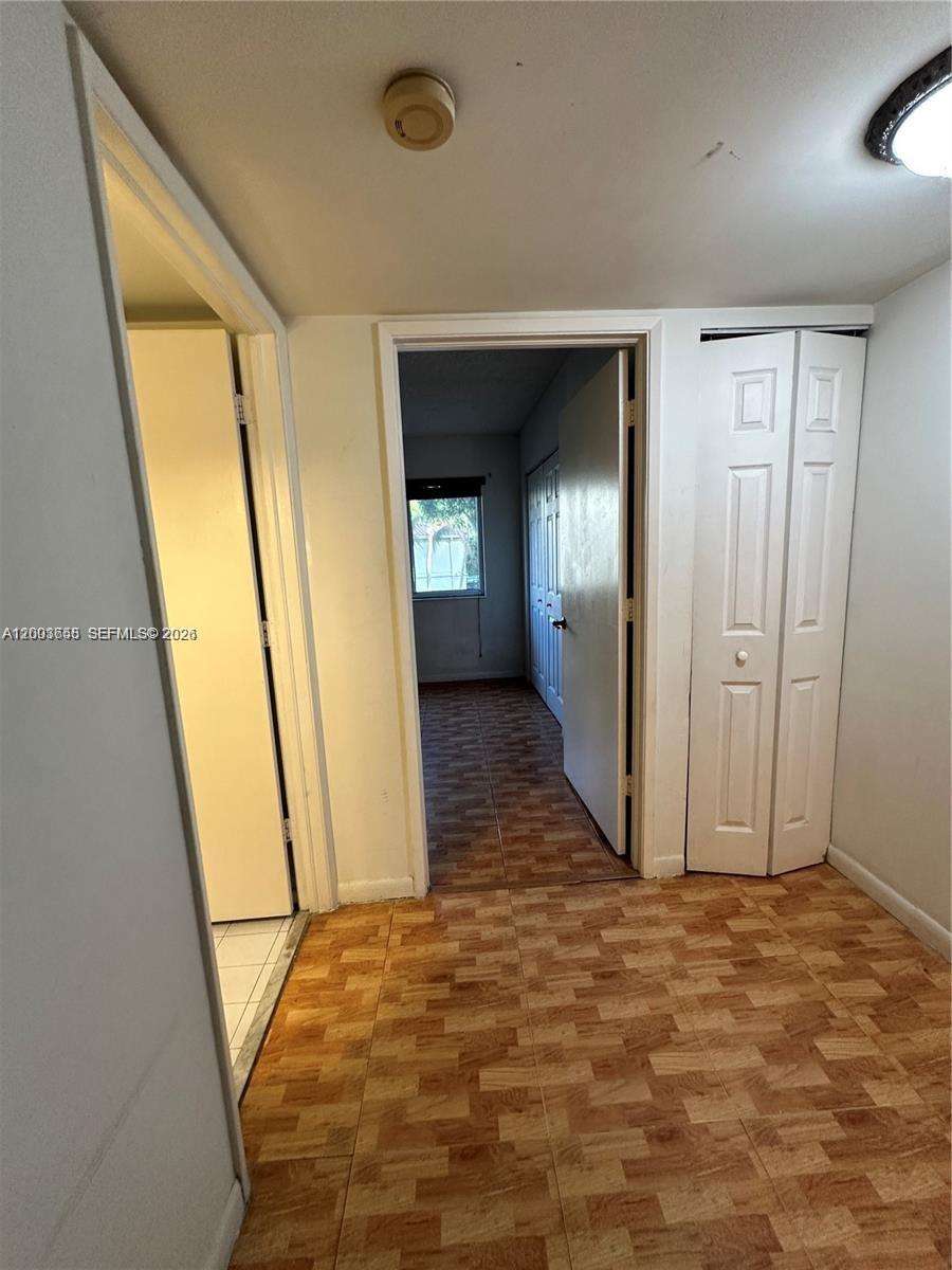 A hallway with wood-look tile flooring leads to a bedroom with a window — 551 NW 82nd Ave # 502, Miami FL 33126, MIAMI, FL